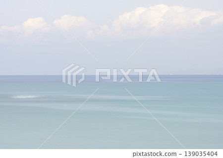 A calm sea in early summer, with a blue gradient background captured using a slow shutter speed. 139035404