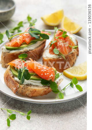 Salmon avocado toasts with cream cheese and lemon on plate Salmon avocado toasts with cream cheese and lemon on plate 139036536