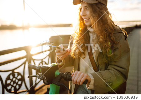 Woman driving electric scooter through city. Ecological transportation. Travel, tourism concept. 139036939