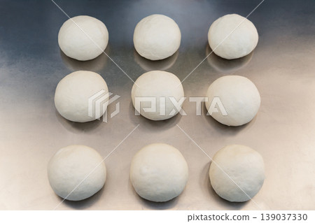 Top view of fresh raw dough balls on a silver metal tray for artisan bread baking. Top view of fresh raw dough balls on a silver metal tray for artisan bread baking. 139037330