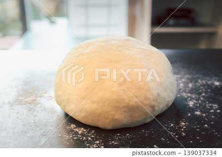Raw fresh yeast dough ball for bread or pizza in kitchen counter with flour dust. Raw fresh yeast dough ball for bread or pizza in kitchen counter with flour dust. 139037334