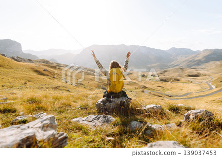 Traveler woman with a bright yellow backpack strolls through golden meadows. Active lifestyle Traveler woman with a bright yellow backpack strolls through golden meadows. Active lifestyle 139037453