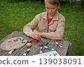 Boy turns humble stones into a rainbow harvest painting tiny avocado, carrot, eggplant with care. 139038091