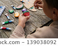 Boy paints strawberries on stones, carrots on pebbles making the most adorable stone fruit and veggie collection ever. 139038092