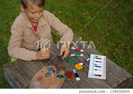 Flat stones become his canvas, and fruits and veggies become his art. A colorful masterpiece in the making. Flat stones become his canvas, and fruits and veggies become his art. A colorful masterpiece in the making. 139038093