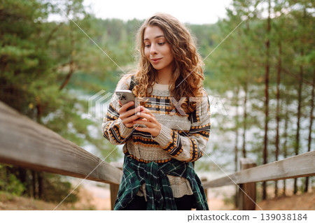Portrait of a female traveler using her phone in the forest. Nice walk in the forest alone. Blogging 139038184