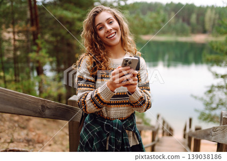 Portrait of a female traveler using her phone in the forest. Nice walk in the forest alone. Blogging 139038186