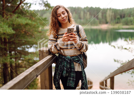 Portrait of a female traveler using her phone in the forest. Nice walk in the forest alone. Blogging 139038187