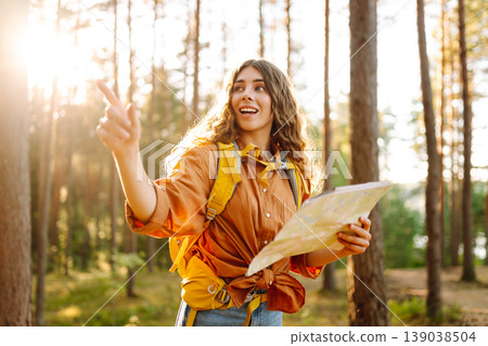 Young woman holding map in forest. Relaxed woman hiker looking navigation searching route. Young woman holding map in forest. Relaxed woman hiker looking navigation searching route. 139038504