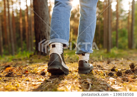 Hiker's boots stepping on a blanket of fallen autumnal orange leaves in the forest. Travel 139038508