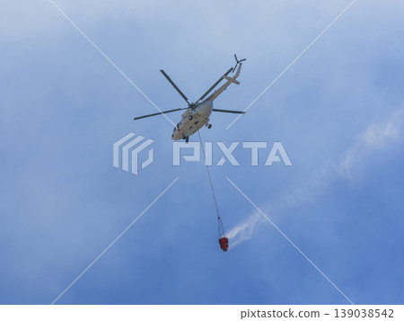 A firefighting helicopter carrying water to a forest fire A firefighting helicopter carrying water to a forest fire 139038542