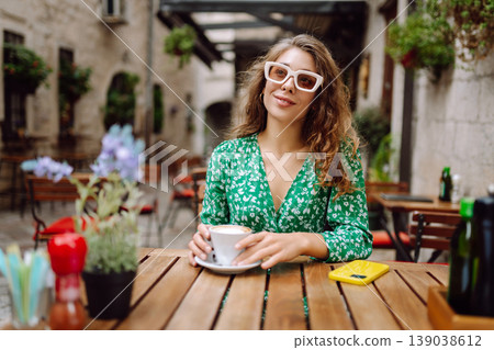 Young woman in a green dress smiles while using her yellow smartphone. Travel, tourism, technology Young woman in a green dress smiles while using her yellow smartphone. Travel, tourism, technology 139038612