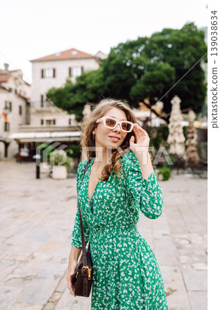 Happy female tourist in beautiful dress walking in the street of the city. Fashion style. Happy female tourist in beautiful dress walking in the street of the city. Fashion style. 139038634