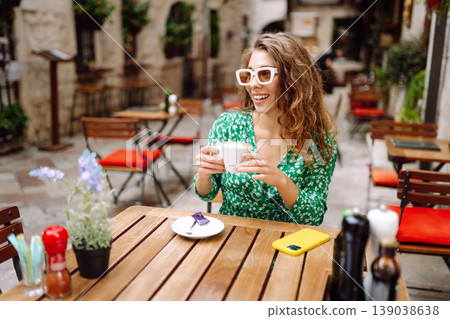 Happy young woman drinking tea, coffee while sitting in a Cafe. People, fashion, lifestyle Happy young woman drinking tea, coffee while sitting in a Cafe. People, fashion, lifestyle 139038638