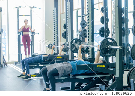 Men and women exercising at a fitness gym Men and women exercising at a fitness gym 139039620