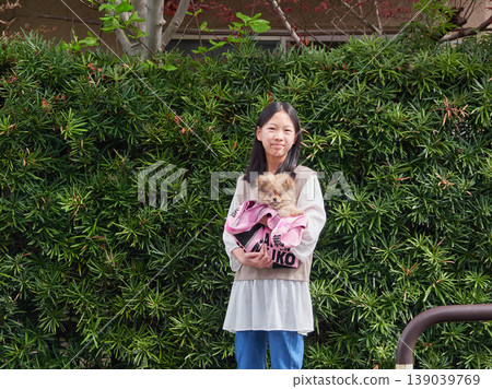 A middle school girl playing with a cute Pomeranian puppy in a park in springtime. A middle school girl playing with a cute Pomeranian puppy in a park in springtime. 139039769