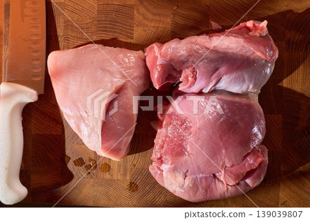 Meat on wood with lighting. Plateful of uncooked meat displayed on rustic wood with dramatic shadows and glossy fat highlights in cozy kitchen Meat on wood with lighting. Plateful of uncooked meat displayed on rustic wood with dramatic shadows and glossy fat highlights in cozy kitchen 139039807