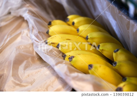 Bananas stacked inside plastic wrapping at a local market during the daytime hours 139039812