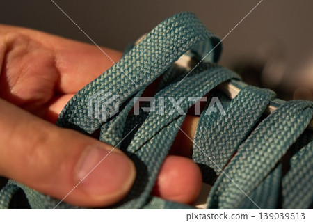 Closeup of shoelace adjustment. Expert demonstration of tying shoelace with gentle finger contact and natural motion 139039813