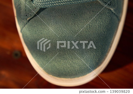 Detailed shot of teal shoe. Closerange photograph highlighting fine nap texture and precise stitching on teal sneaker 139039820