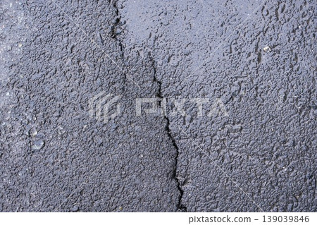 Detailed texture of damp dark asphalt with a deep vertical crack, industrial nature background Detailed texture of damp dark asphalt with a deep vertical crack, industrial nature background 139039846