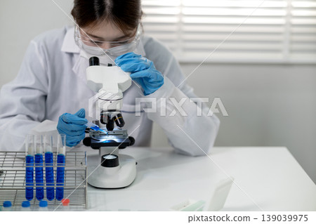 Asian adult female scientist research experiment using microscope analyzing chemical samples modern laboratory medical science discovery development 139039975