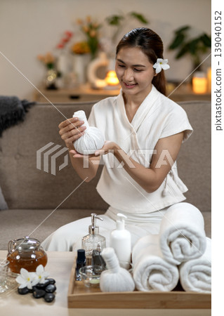 Adult Asian woman spa therapist holding herbal compress ball showing natural wellness treatment tranquil home spa relaxing self care experience Adult Asian woman spa therapist holding herbal compress ball showing natural wellness treatment tranquil home spa relaxing self care experience 139040152