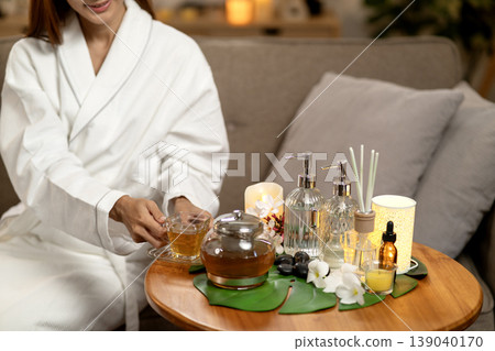 Asian adult woman enjoying hot herbal tea home spa treatment bath robe wellness peaceful atmosphere luxury selfcare Asian adult woman enjoying hot herbal tea home spa treatment bath robe wellness peaceful atmosphere luxury selfcare 139040170