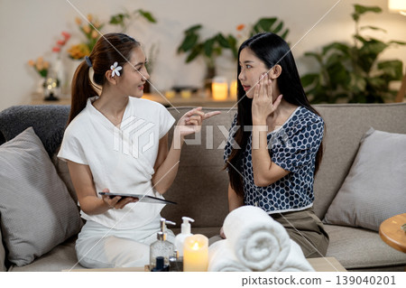 Asian spa therapist adult woman consults client skincare treatment home wellness expert offers beauty advice cozy environment client listens actively Asian spa therapist adult woman consults client skincare treatment home wellness expert offers beauty advice cozy environment client listens actively 139040201