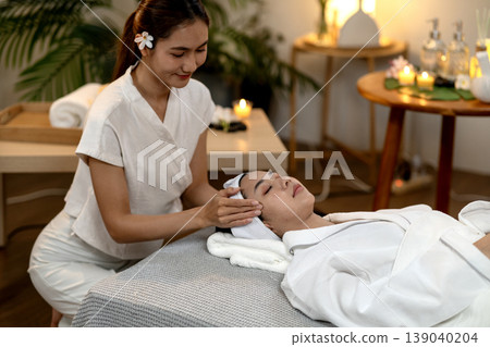Asian adult women receiving professional facial massage relaxing spa treatment peaceful wellness luxury health care at tranquil beauty salon atmosphere Asian adult women receiving professional facial massage relaxing spa treatment peaceful wellness luxury health care at tranquil beauty salon atmosphere 139040204