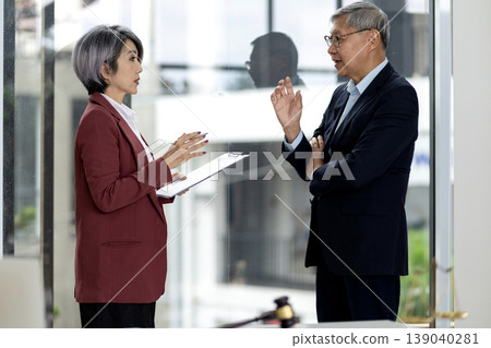Asian business professionals legal consultants discuss important documents in modern office setting for strategic planning and advice 139040281