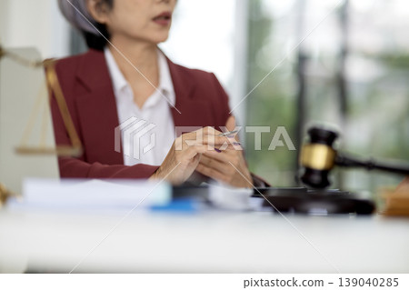 Adult Asian lawyer professional attorney discusses legal case holds pen provides expert advice modern law office courtroom setting Adult Asian lawyer professional attorney discusses legal case holds pen provides expert advice modern law office courtroom setting 139040285