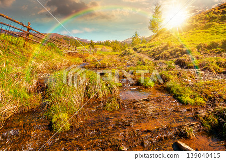 sunset over rural scenery in carpathian mountains. simple view of a countryside mountain landscape during springtime. brook near the grassy hills. weather with rainbow 139040415