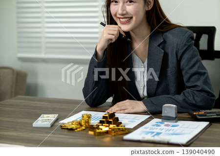 Asian businesswoman managing wealth investments financial planning analyzing market data with gold money currency office environment Asian businesswoman managing wealth investments financial planning analyzing market data with gold money currency office environment 139040490