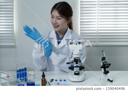 Asian adult woman scientist prepare laboratory work put on protective blue gloves for research experiment medical safety focus professionalism scientific discovery 139040496
