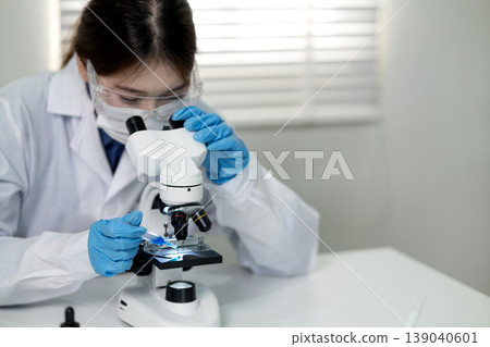 Asian woman scientist conducts precise lab experiment using microscope discovering new medical science technology professional research in laboratory Asian woman scientist conducts precise lab experiment using microscope discovering new medical science technology professional research in laboratory 139040601