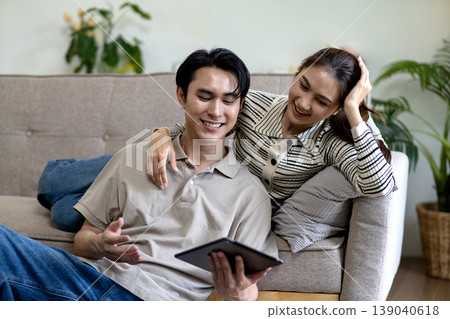 Asian adult couple view entertainment digital content enjoying connection relaxation home modern living room comfortable cozy space 139040618