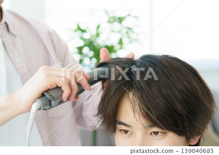 Close-up of a young Japanese hairdresser's hands curling hair. Close-up of a young Japanese hairdresser's hands curling hair. 139040685
