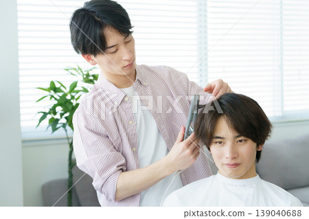 A young Japanese hairdresser curling hair with a curling iron. A young Japanese hairdresser curling hair with a curling iron. 139040688