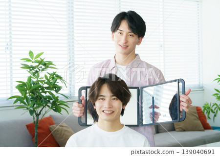 A young Japanese hairdresser shows the cut hairstyle in the mirror. A young Japanese hairdresser shows the cut hairstyle in the mirror. 139040691