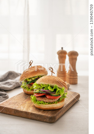 A delicious homemade burger with beef, tomato, cheese, and lettuce on a cutting board A delicious homemade burger with beef, tomato, cheese, and lettuce on a cutting board 139040709