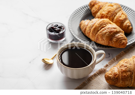 Cup of espresso coffee and fresh croissants on a light marble background with berry jam and spoon Cup of espresso coffee and fresh croissants on a light marble background with berry jam and spoon 139040718