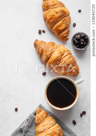 Cup of espresso coffee and fresh croissants on a light textured background with berry jam  139040720