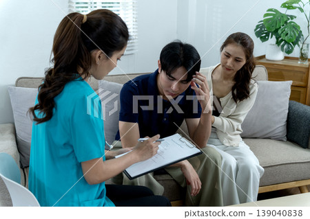 Asian adult couple receives mental health consultation from professional at home office coping with stress anxiety during psychiatric evaluation report discussion 139040838