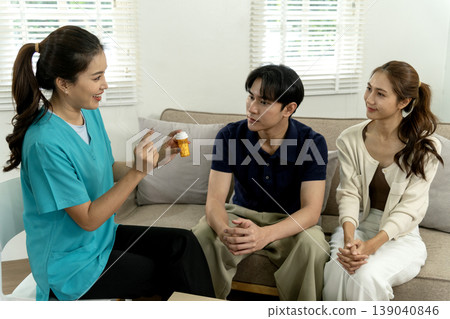 Asian healthcare professional educates young adult couple about prescription medication providing home health guidance discussing treatment plans at modern residence Asian healthcare professional educates young adult couple about prescription medication providing home health guidance discussing treatment plans at modern residence 139040846
