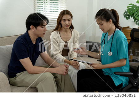 Asian doctor explaining medical advice to adult couple at home during health consultation planning wellness program Asian doctor explaining medical advice to adult couple at home during health consultation planning wellness program 139040851