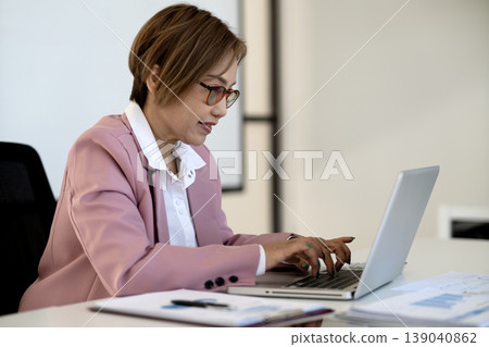 Asian adult businesswoman professional work on laptop computer office desk documents female leader executive career digital tasks remote management Asian adult businesswoman professional work on laptop computer office desk documents female leader executive career digital tasks remote management 139040862