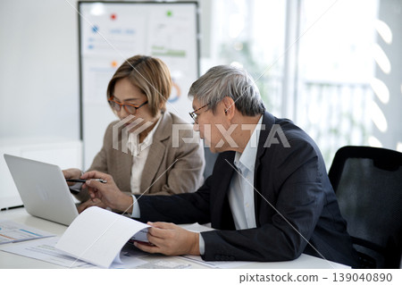 Adult Asian business professionals collaborate discuss project strategy review data analysis reports in modern bright office environment Adult Asian business professionals collaborate discuss project strategy review data analysis reports in modern bright office environment 139040890