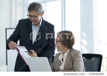 Asian business adult professionals discuss important financial documents project reports data analysis work together office meeting corporate strategy for success Asian business adult professionals discuss important financial documents project reports data analysis work together office meeting corporate strategy for success 139040891