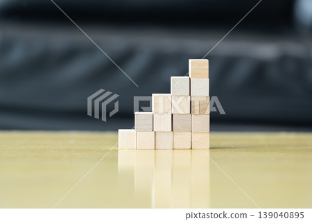 Wooden blocks and cubes form rising step shapes on a table in front of a child, combining gradual learning progress with playful problem solving and early thinking development. Wooden blocks and cubes form rising step shapes on a table in front of a child, combining gradual learning progress with playful problem solving and early thinking development. 139040895